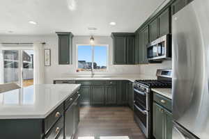 Kitchen featuring stainless steel appliances, sink, dark wood-type flooring, and a textured ceiling