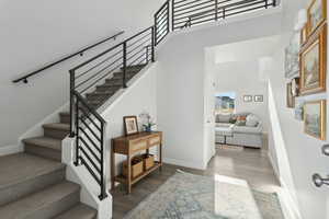 Staircase featuring hardwood / wood-style floors and a towering ceiling