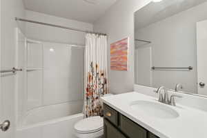 Full bathroom with vanity, shower / tub combo with curtain, and toilet