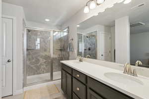 Bathroom featuring vanity, tile patterned flooring, and a shower with shower door