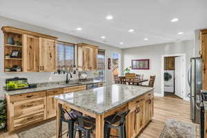 Kitchen with light stone counters, stainless steel appliances, washer / dryer, and sink