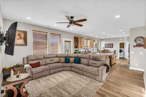 Living room featuring washer / clothes dryer, sink, ceiling fan, and light wood-type flooring