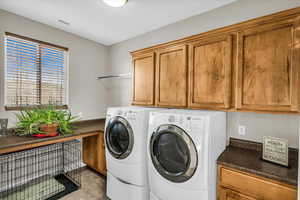 Clothes washing area featuring cabinets and washer and dryer