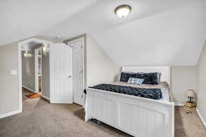 Bedroom with vaulted ceiling and carpet