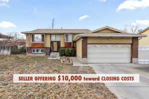 Split foyer home featuring fence, brick siding, driveway, and a garage