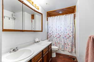 Full bathroom with wood-type flooring, vanity, shower / bath combination with curtain, and toilet