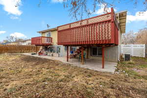 Back of property featuring a lawn, a wooden deck, cooling unit, and a patio area