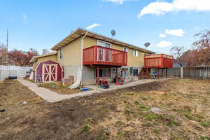 Back of property with a wooden deck and a storage unit