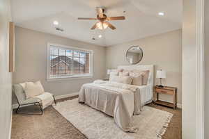 Carpeted bedroom featuring ceiling fan and vaulted ceiling