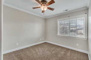 Carpeted spare room with crown molding and ceiling fan