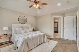 Bedroom with lofted ceiling, a spacious closet, light colored carpet, and ceiling fan