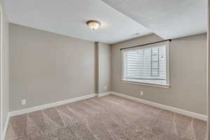 Carpeted empty room with a textured ceiling