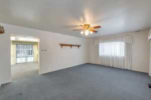 Unfurnished room featuring ceiling fan and dark colored carpet