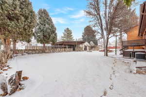 Yard covered in snow featuring cooling unit and a jacuzzi