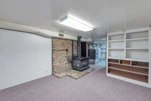 Basement featuring a wood stove and carpet flooring