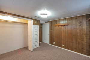 Unfurnished bedroom with wood walls and carpet flooring