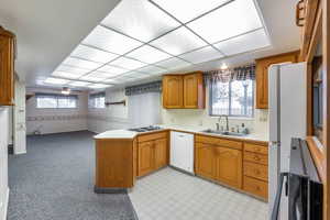 Kitchen featuring white appliances, plenty of natural light, kitchen peninsula, and sink