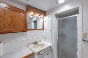 Bathroom featuring vanity, a shower with shower door, and backsplash