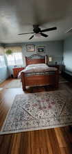 Bedroom with ceiling fan, wood-type flooring, and a textured ceiling