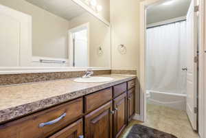 Full bathroom with tile patterned flooring, vanity, shower / bath combo with shower curtain, and toilet