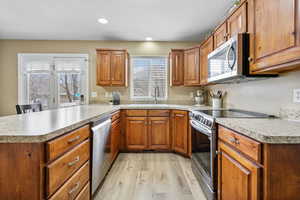 Kitchen with sink, light wood-type flooring, kitchen peninsula, and appliances with stainless steel finishes