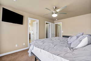 Carpeted bedroom featuring ensuite bathroom, a textured ceiling, and ceiling fan