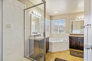 Bathroom featuring plus walk in shower, tile patterned floors, vanity, and a textured ceiling