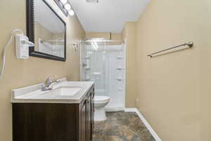 Bathroom with vanity, an enclosed shower, a textured ceiling, and toilet