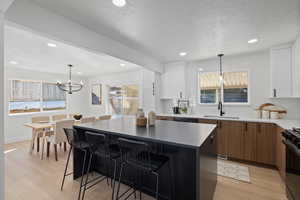 Kitchen with black gas range oven, sink, a kitchen island, and white cabinets