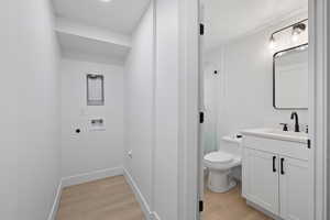 Bathroom featuring hardwood / wood-style flooring, vanity, walk in shower, and toilet