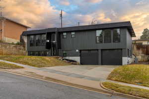 View of front of home featuring a garage, a lawn, and central air condition unit