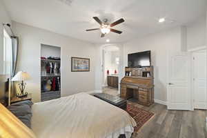 Bedroom with ensuite bathroom, a spacious closet, a closet, hardwood / wood-style flooring, and ceiling fan