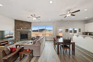 Living room featuring hardwood / wood-style flooring, a mountain view, a stone fireplace, and ceiling fan