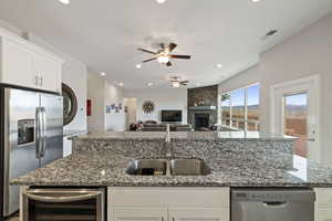 Kitchen featuring sink, appliances with stainless steel finishes, white cabinetry, wine cooler, and dark stone counters