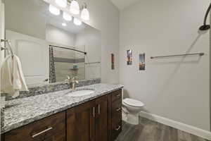 Bathroom with vanity, tiled shower, hardwood / wood-style floors, and toilet