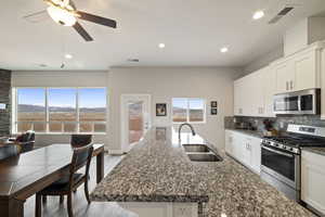 Kitchen with stainless steel appliances, sink, white cabinets, and backsplash