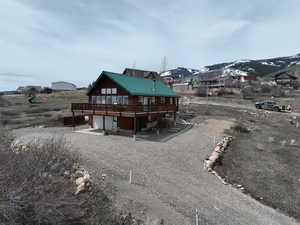Back of house with an attached garage, dirt driveway, a deck with mountain view, and metal roof