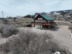 Rear view of house featuring an attached garage, a wooden deck, and driveway