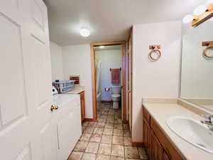Full bathroom with separate washer and dryer, vanity, shower / tub combo, toilet, and a textured ceiling