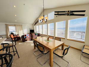 Dining area featuring a notable chandelier, carpet flooring, vaulted ceiling, and a wealth of natural light