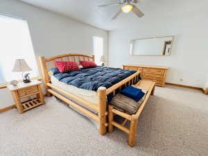 Carpeted bedroom featuring ceiling fan and a textured ceiling