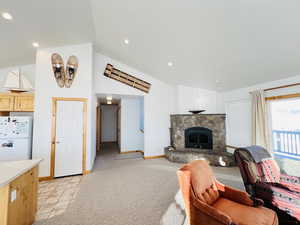 Living room with high vaulted ceiling, a fireplace, and light colored carpet