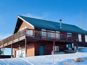 Snow covered property featuring a garage and a deck