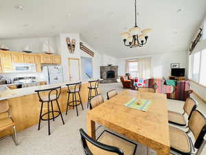 Dining space with plenty of natural light, a chandelier, high vaulted ceiling, and light carpet