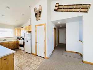 Kitchen featuring white appliances, high vaulted ceiling, and sink