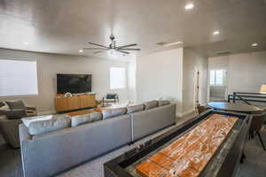 Carpeted living room featuring ceiling fan, a healthy amount of sunlight, and a textured ceiling