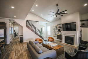 Living room featuring hardwood / wood-style floors, vaulted ceiling, and ceiling fan