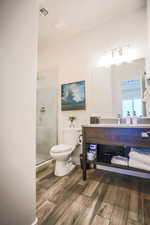 Bathroom with vanity, a shower with shower door, hardwood / wood-style floors, and toilet