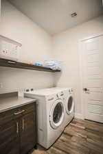 Laundry area featuring washing machine and dryer and dark wood-type flooring