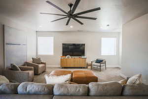 Living room featuring ceiling fan, a healthy amount of sunlight, light carpet, and a textured ceiling